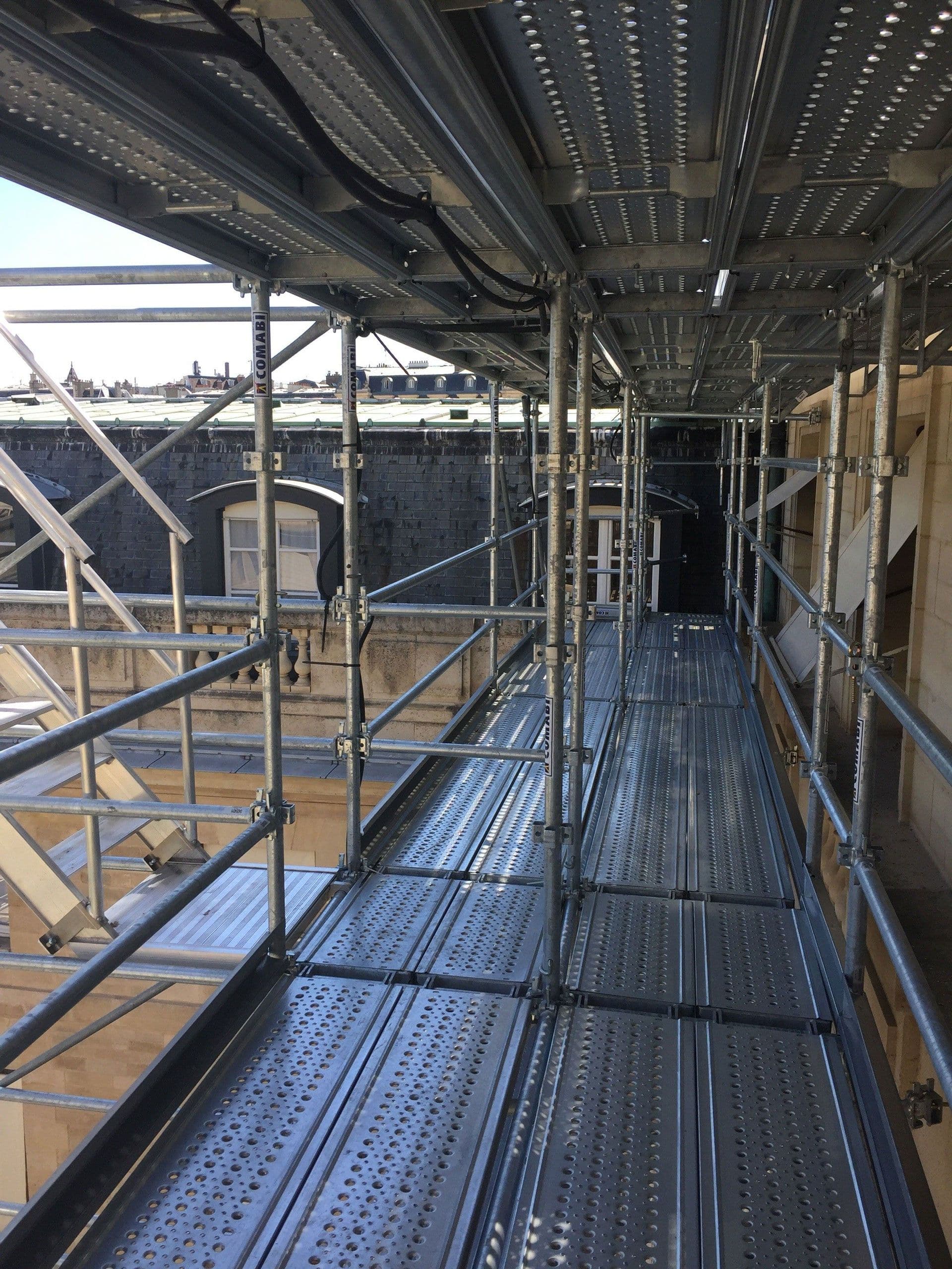A long metal scaffolding walkway with railings on both sides for construction site access.