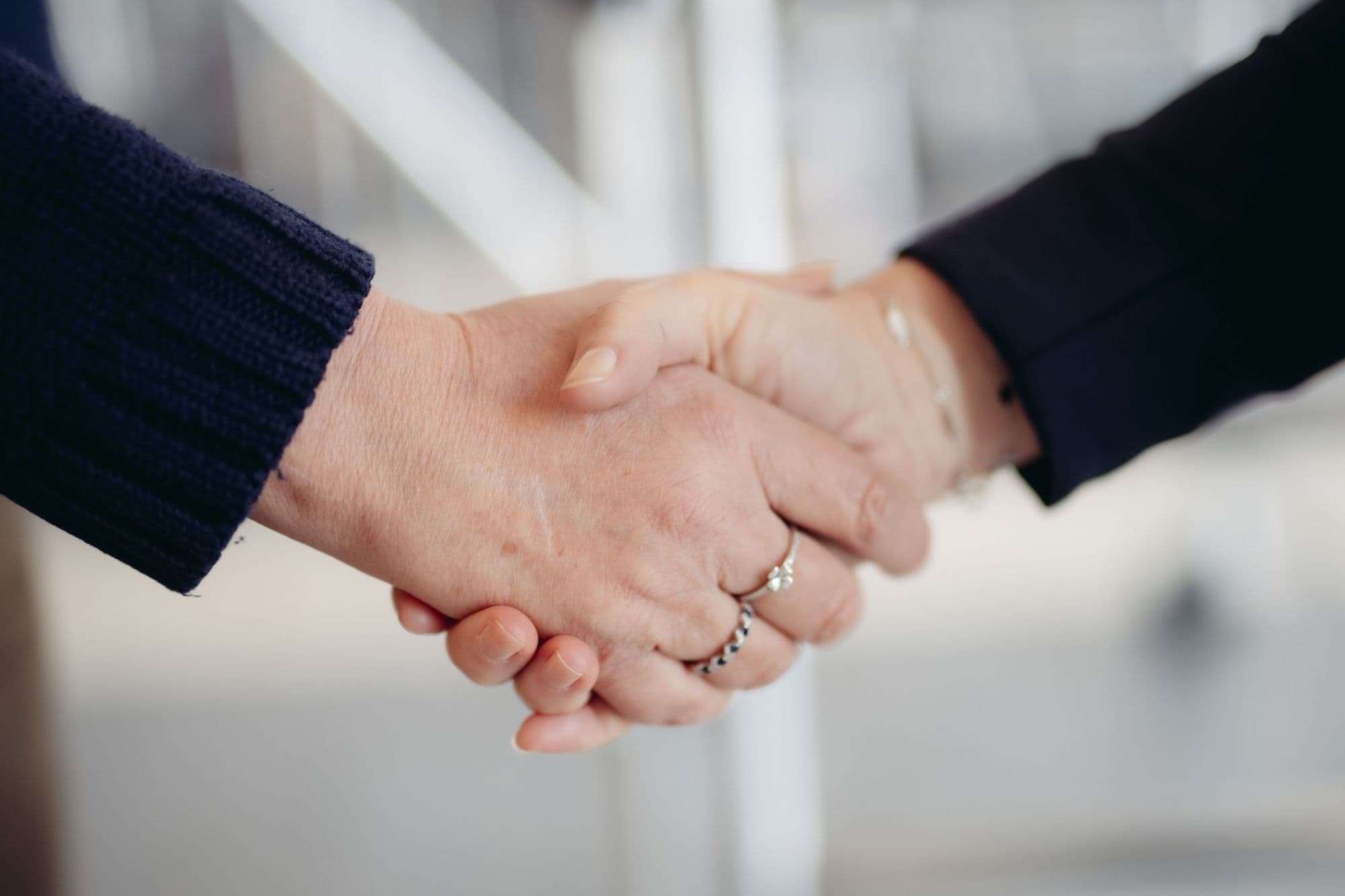 Two individuals shake hands, symbolizing agreement, partnership, or a warm greeting.